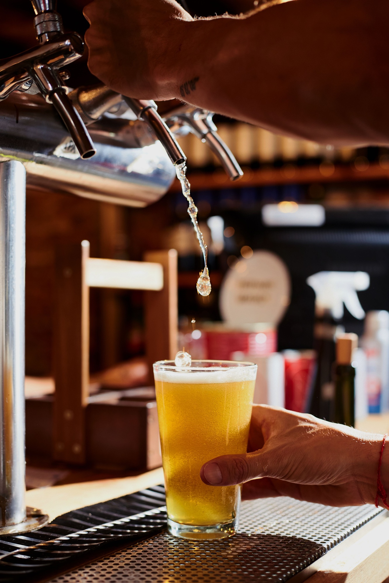Vertical shot of a man drafting a beer at a bar